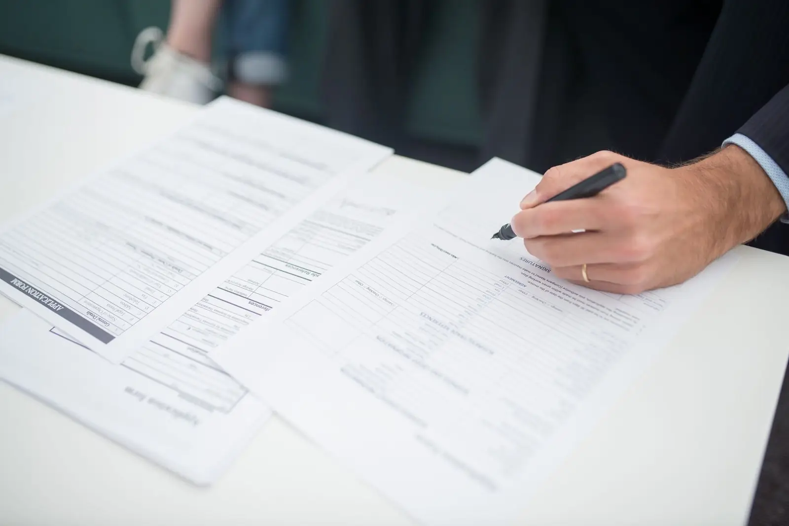 Hand completing an application form among other forms