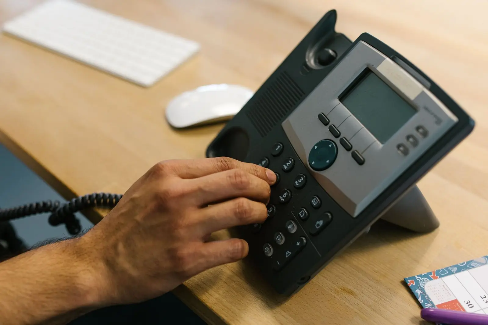 Hand dialling a desk phone in an office