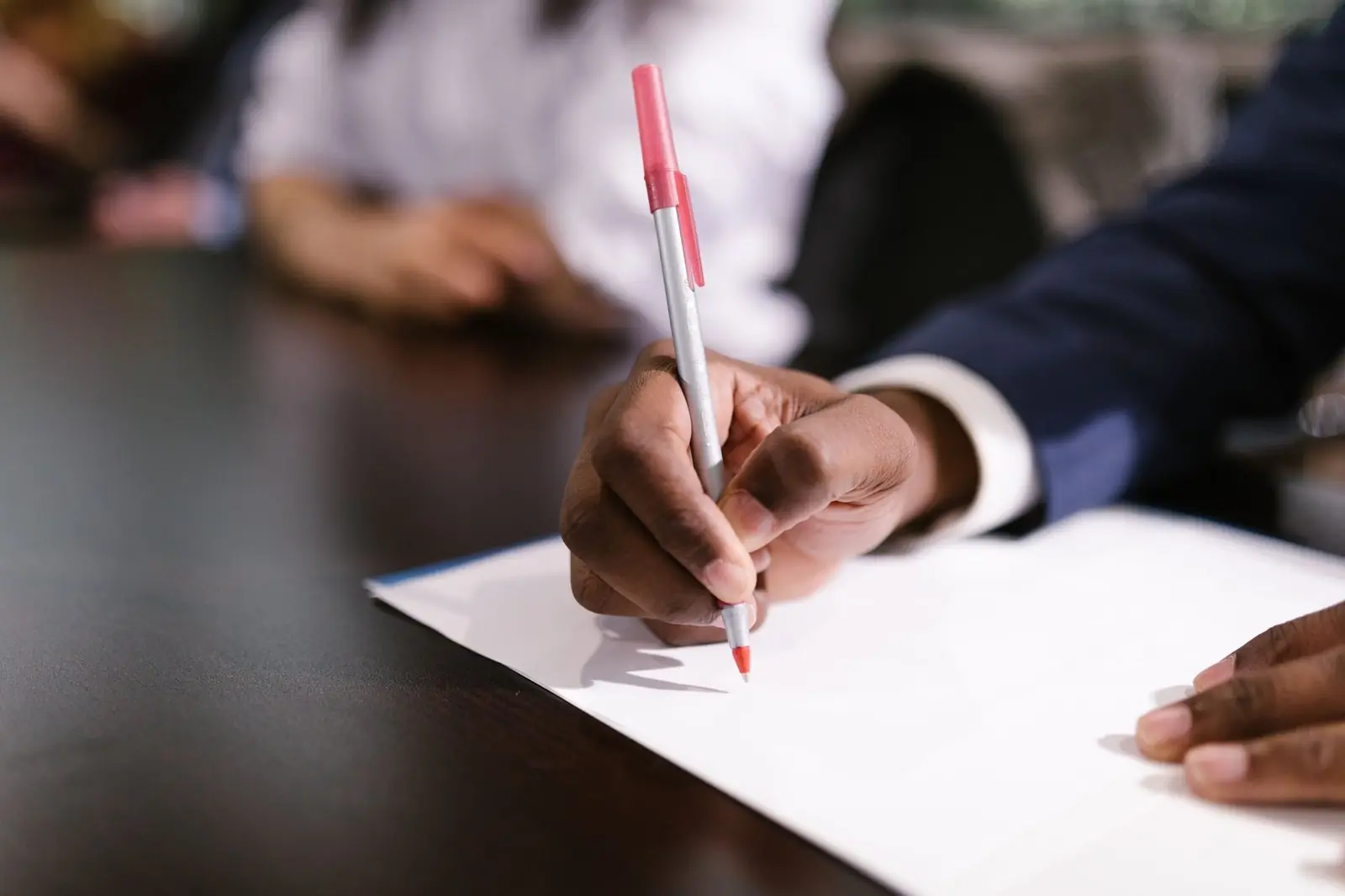 Hand writing on a sheet of paper at a table