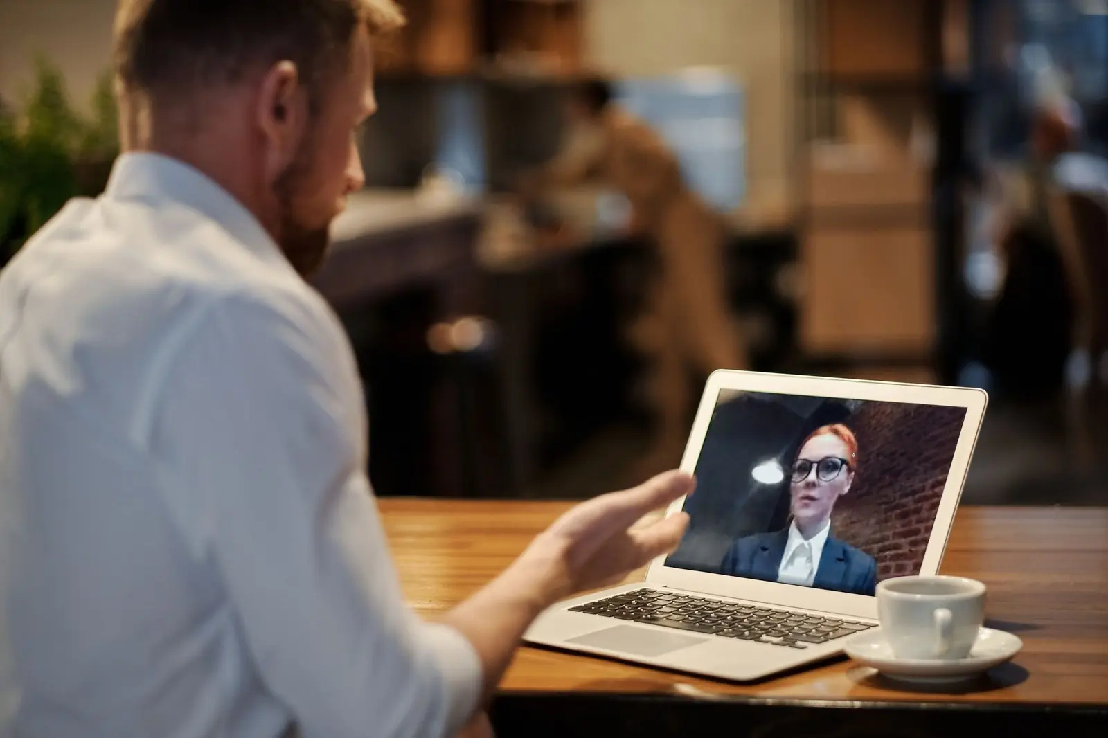 A man at a laptop in a video call, with papers beside him