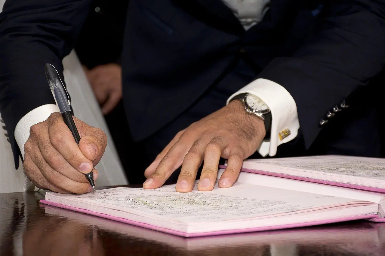 Man in a suit signing a bound register