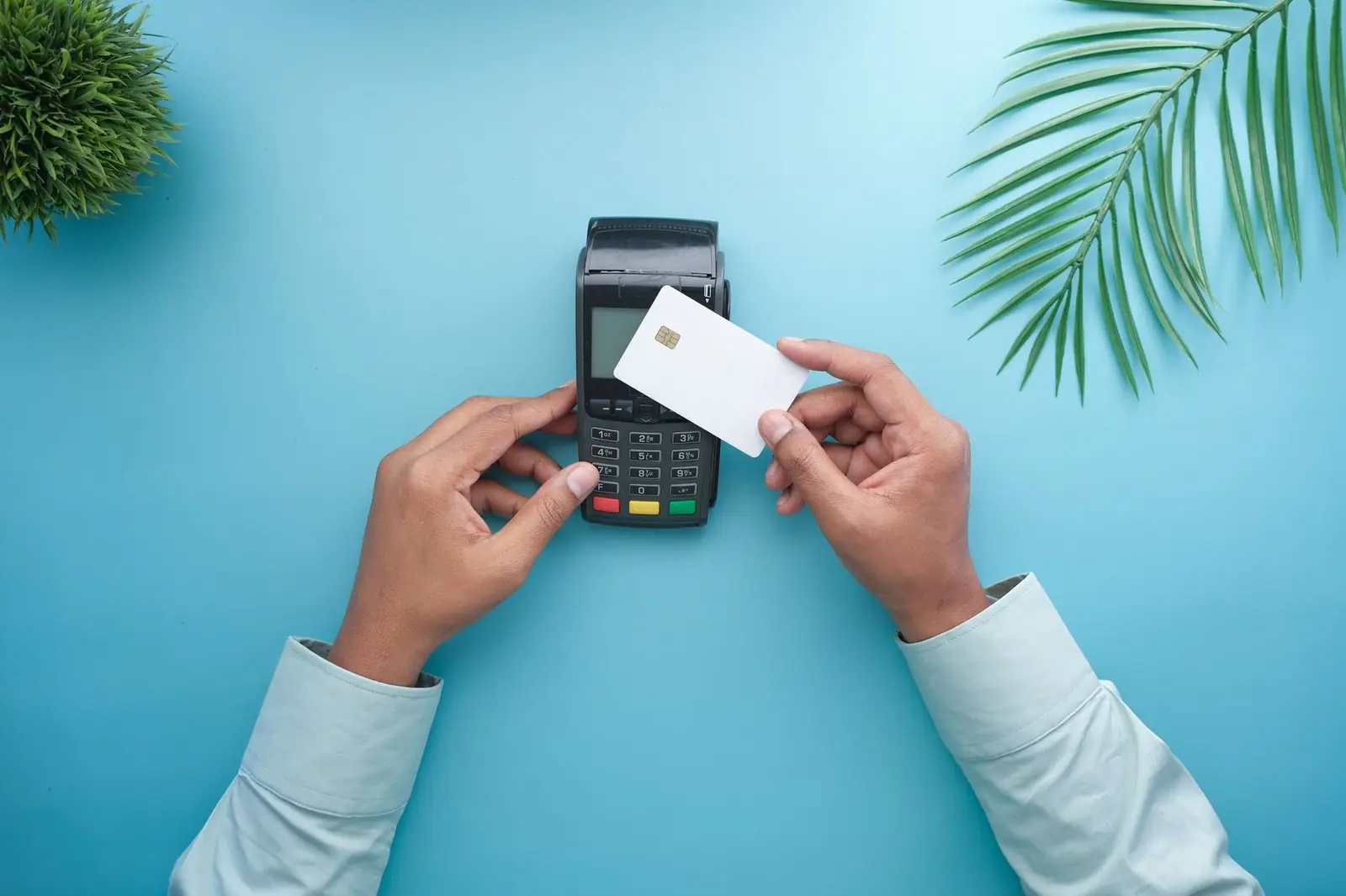 Hands holding a card over a payment terminal