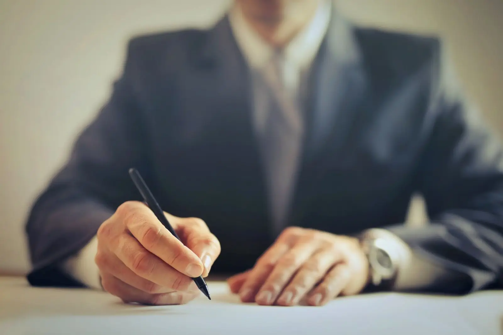Man in a suit about to sign a document