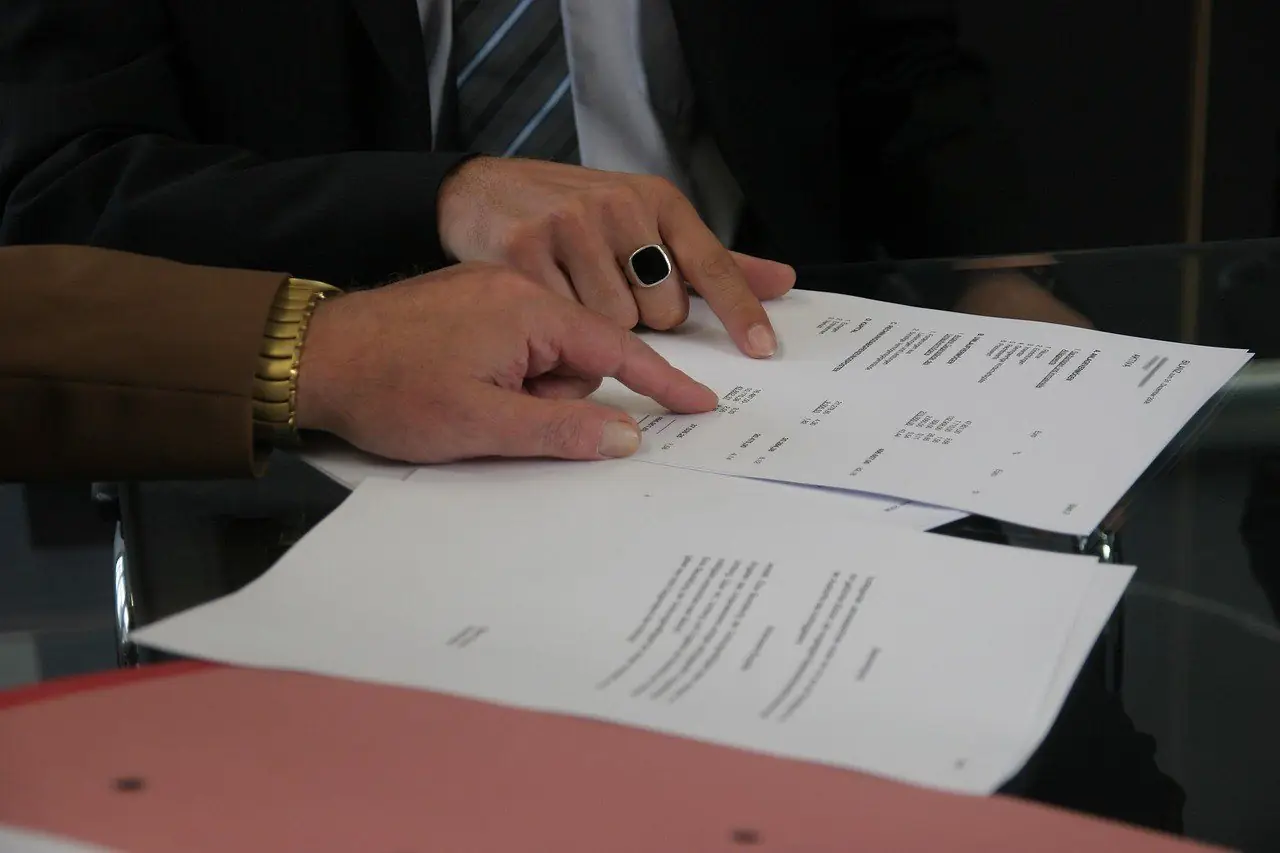 Two people checking the lines of a document before signing