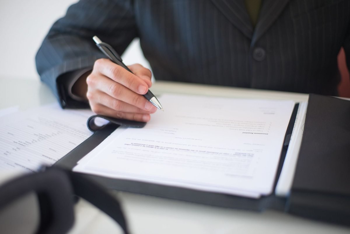Hand signing papers in a folder, a typical notarised document for Dubai court services