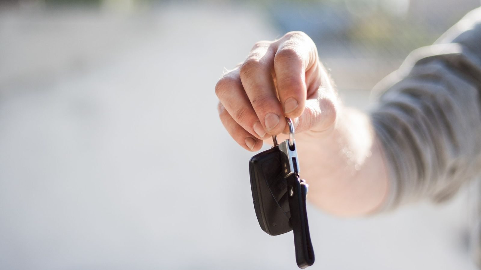 Hand passing a car key to another person, as in a power of attorney for a car sale