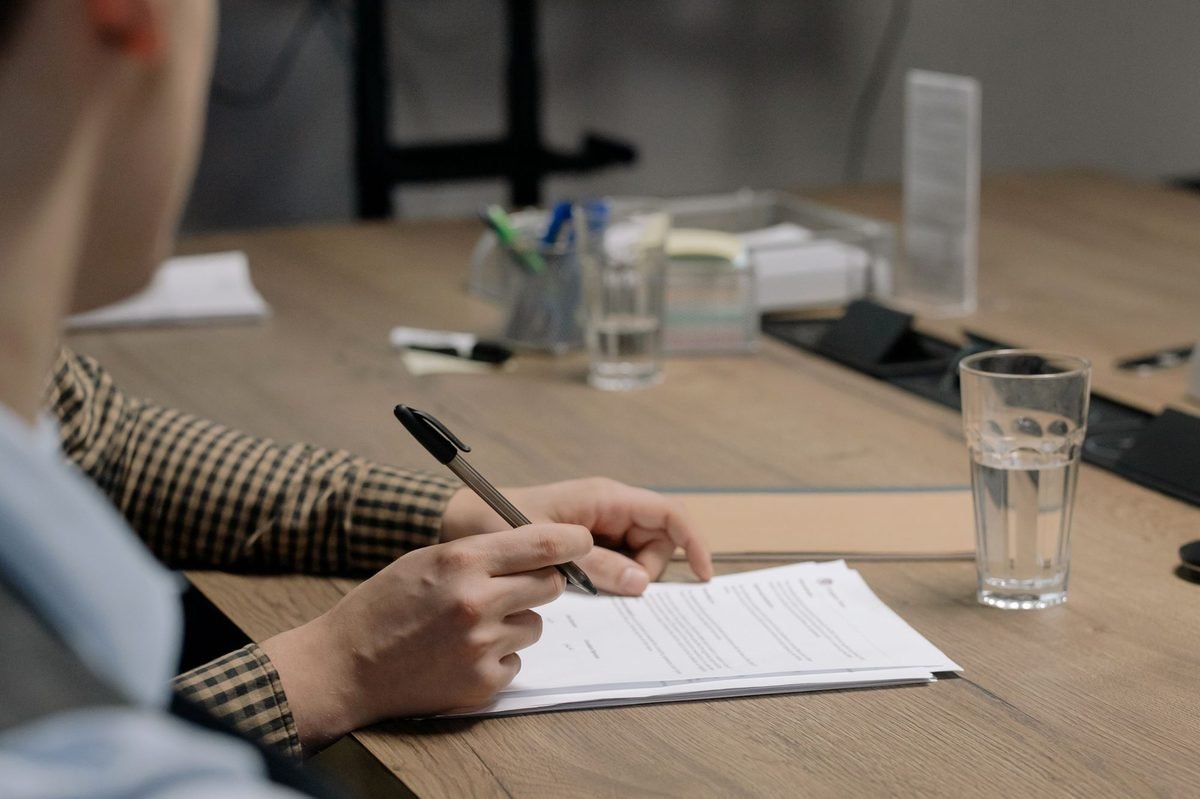 Hands signing a document on a wooden office table for an IVS Global Dubai power of attorney